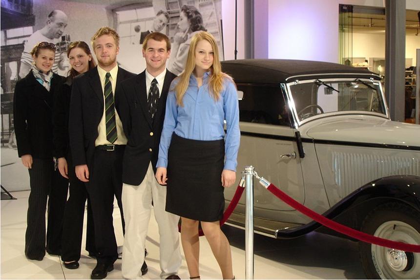 Students stand in front of a car